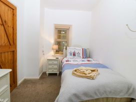 A bedroom with a single bed and bedside table at Farm Cottage in Cemaes Bay