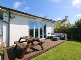 A garden with a table and bench on a deck at Farm Cottage in Cemaes Bay