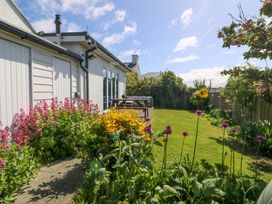 A garden with flowers and a wooden deck at Farm Cottage in Cemaes Bay