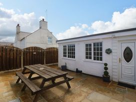 An outdoor area with a table and benches at Farm Cottage in Cemaes Bay