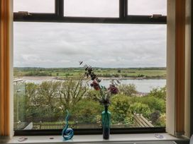 A window with a vase and flowers overlooking a landscape at Gwylan Uchaf in Y Felinheli