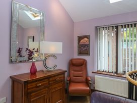 A living room with a chair and lamp at Gwylan Uchaf in Y Felinheli