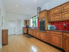 A kitchen with wooden cabinets and appliances at Gwylan Uchaf in Y Felinheli