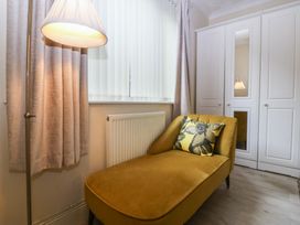 A living room with a chaise lounge and lamp at Gwylan Uchaf in Y Felinheli
