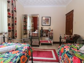 A bedroom with two beds and a mirror at Gwylan Uchaf Y Felinheli