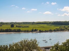 A view of a river with boats and green fields at Gwylan Uchaf Y Felinheli