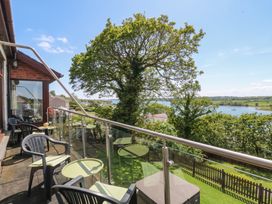 An outdoor area with chairs and a table overlooking a waterway at Gwylan Uchaf Y Felinheli