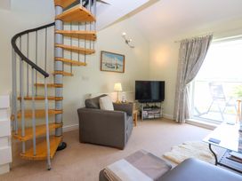 A living room with a spiral staircase and a TV at Machlud Ynys in Y Felinheli