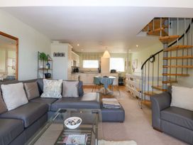 A living room with a staircase and kitchen area at Machlud Ynys in Y Felinheli