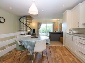 A dining room with a staircase and kitchen cabinets at Machlud Ynys Y Felinheli
