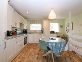 A kitchen with a table and chairs at Machlud Ynys, Y Felinheli