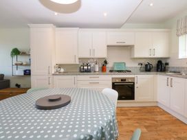 A kitchen with cabinets and a dining table at Machlud Ynys Y Felinheli