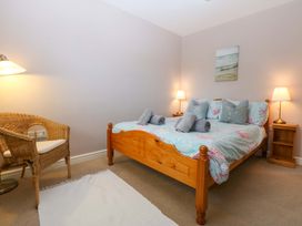 A bedroom with a bed and chair at Machlud Ynys in Y Felinheli