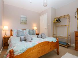 A bedroom with a bed and a storage rack at Machlud Ynys, Y Felinheli