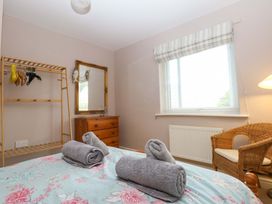 A bedroom with towels on bed and dresser at Machlud Ynys, Y Felinheli