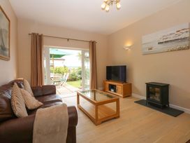 A living room with a sofa, tv, and coffee table at Menai Cottage in Brynsiencyn