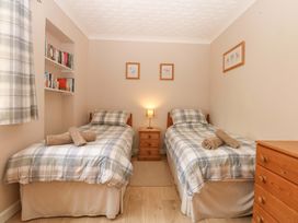 A bedroom with twin beds and bookshelf at Menai Cottage Brynsiencyn