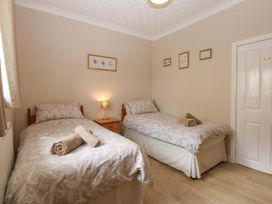 A bedroom with two beds and a lamp at Menai Cottage in Brynsiencyn