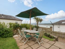 A garden with a table and chairs under a parasol at Menai Cottage in Brynsiencyn