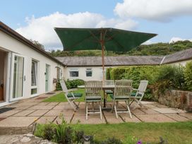 A garden with a table and chairs under a parasol at Menai Cottage in Brynsiencyn