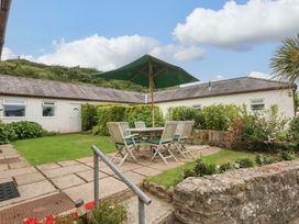 A garden with a table and chairs under an umbrella at Menai Cottage Brynsiencyn