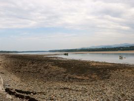 A view of the water and pier with rocks and a boat at Menai Cottage in Brynsiencyn