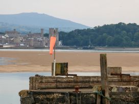 A view of a castle and mountain from a pier at Menai Cottage in Brynsiencyn