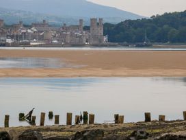 A view of a castle by the water at Menai Cottage in Brynsiencyn