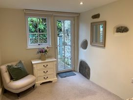 A room with a chair, table, and door at The Honey Pot in Garndolbenmaen