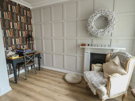 A snug with a desk, chair and a fireplace at Tri Raglan Mawr in Beaumaris