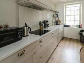 A kitchen with a microwave, kettle, coffee maker, and sink at Tri Raglan Mawr in Beaumaris