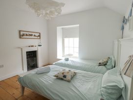 A bedroom with two single beds and a window at Tri Raglan Mawr Beaumaris