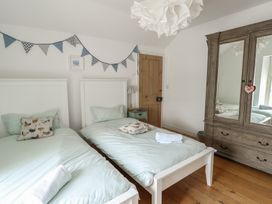 A bedroom with two single beds and a wardrobe at Tri Raglan Mawr in Beaumaris