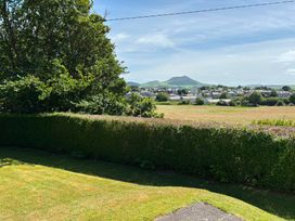 A garden with a hedge and a view of houses and mountains at Ty Bryn - Nefyn Morfa Nefyn