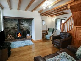 A living room with a fireplace and wooden beams at Tyn y Mynydd in Bull Bay