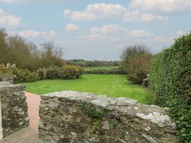 A garden with a stone wall and grass at Tyn y Mynydd in Bull Bay