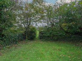A garden area with a gate and trees at Tyn y Mynydd Bull Bay