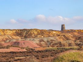 A landscape with a tower and colored mounds at Tyn y Mynydd in Bull Bay
