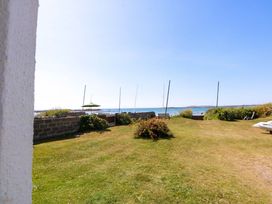 A garden view with grass and sea at Windygates Rhosneigr