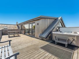 A rooftop deck with a hot tub and wooden bench at Ysbryd y Mynydd in South Stack