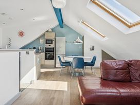 A living room with a sofa, table, and kitchen area at Ysbryd y Mynydd in South Stack