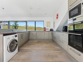 A kitchen with a washing machine and wall ovens at Ysbryd y Mynydd in South Stack