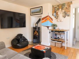 A living room with a mounted TV bean bag stove and a table with baskets and a decorative mannequin torso at Y Stabl in Criccieth