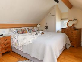 A bedroom with a bed with patterned pillows a wooden nightstand and a wooden dresser with a mirror at Y Stabl in Criccieth