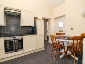 A kitchen with cabinets, a table, and chairs at Clwyd Cottage in St Asaph