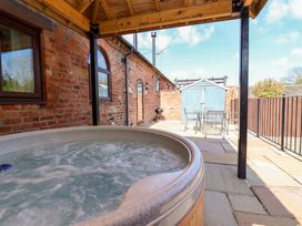 A hot tub with outdoor furniture and a shed at Clwyd Cottage St Asaph