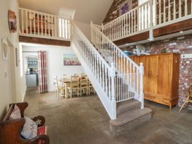 A dining room with a staircase and dining table at Llanallgo Church Rooms
