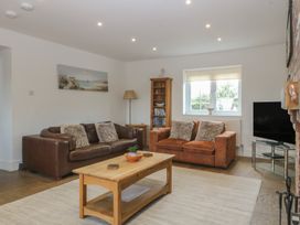 A living room with sofas, a coffee table, and a television at Llanallgo Church Rooms in 