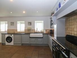 A kitchen with a sink and washing machine at Llanallgo Church Rooms