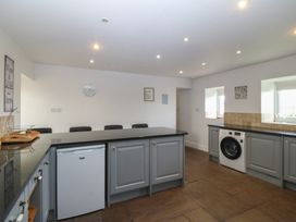 A kitchen with counter, refrigerator, washing machine and seating at Llanallgo Church Rooms